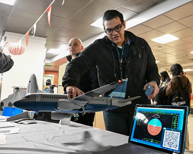Physics club member showing off a plane at the Club Fair